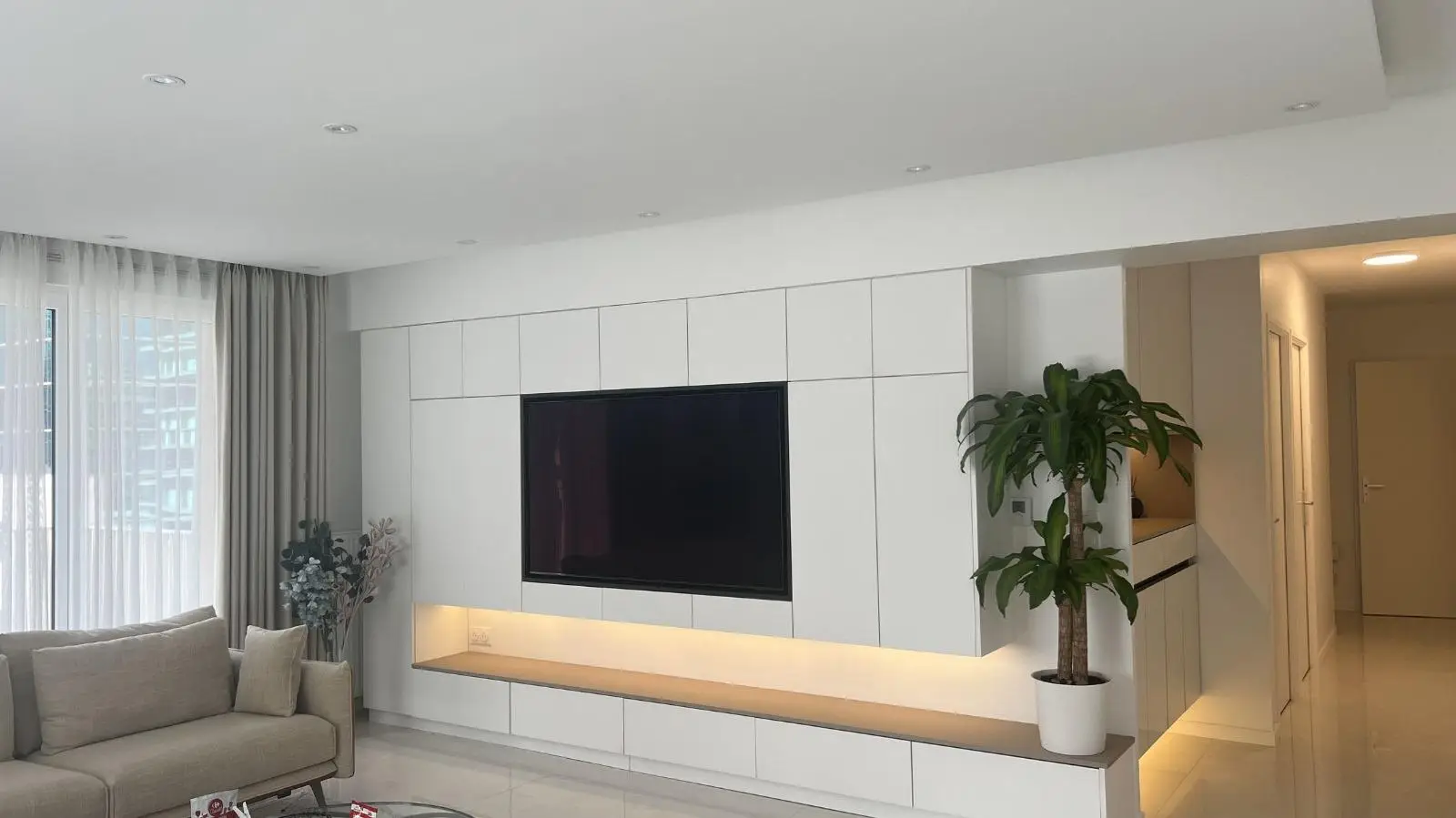 Media wall in matt lacquer with a floating oak shelf and concealed lighting