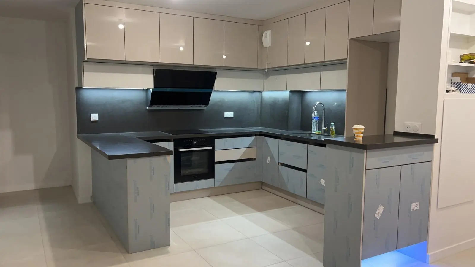 Grey gloss kitchen in an L-shape with stone worktop and under-cabinet lighting