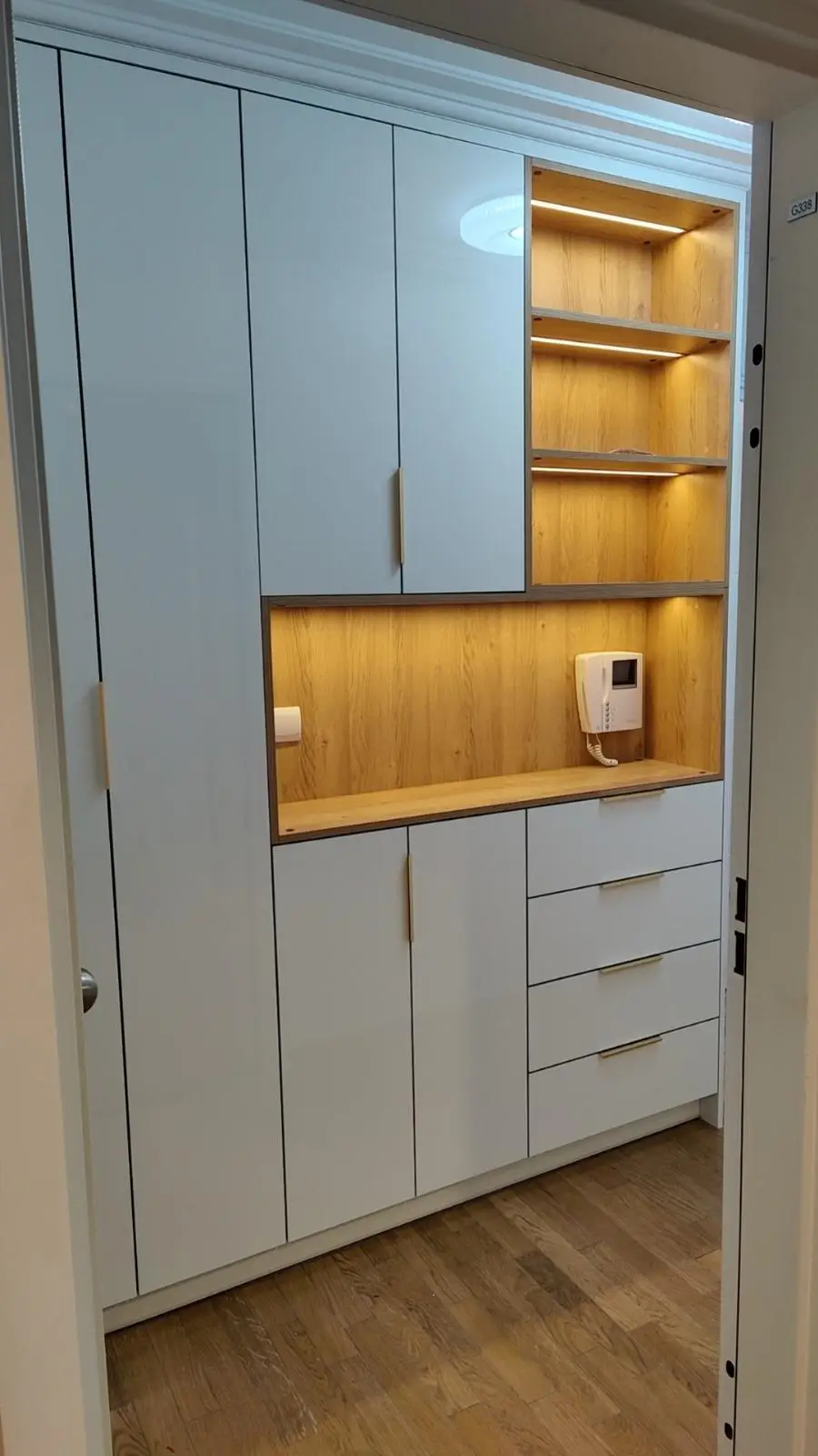 Tall unit detail with an oak-lined open niche, brass-edged pulls and integrated lighting