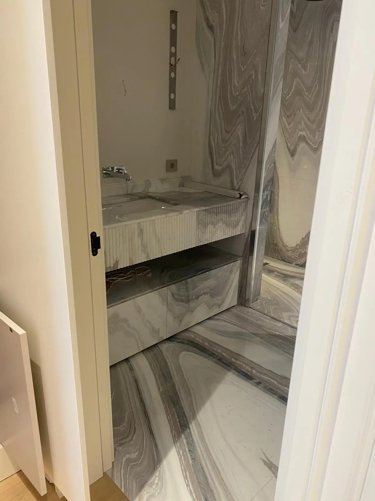 Marble-clad vanity with fitted joinery and concealed lighting
