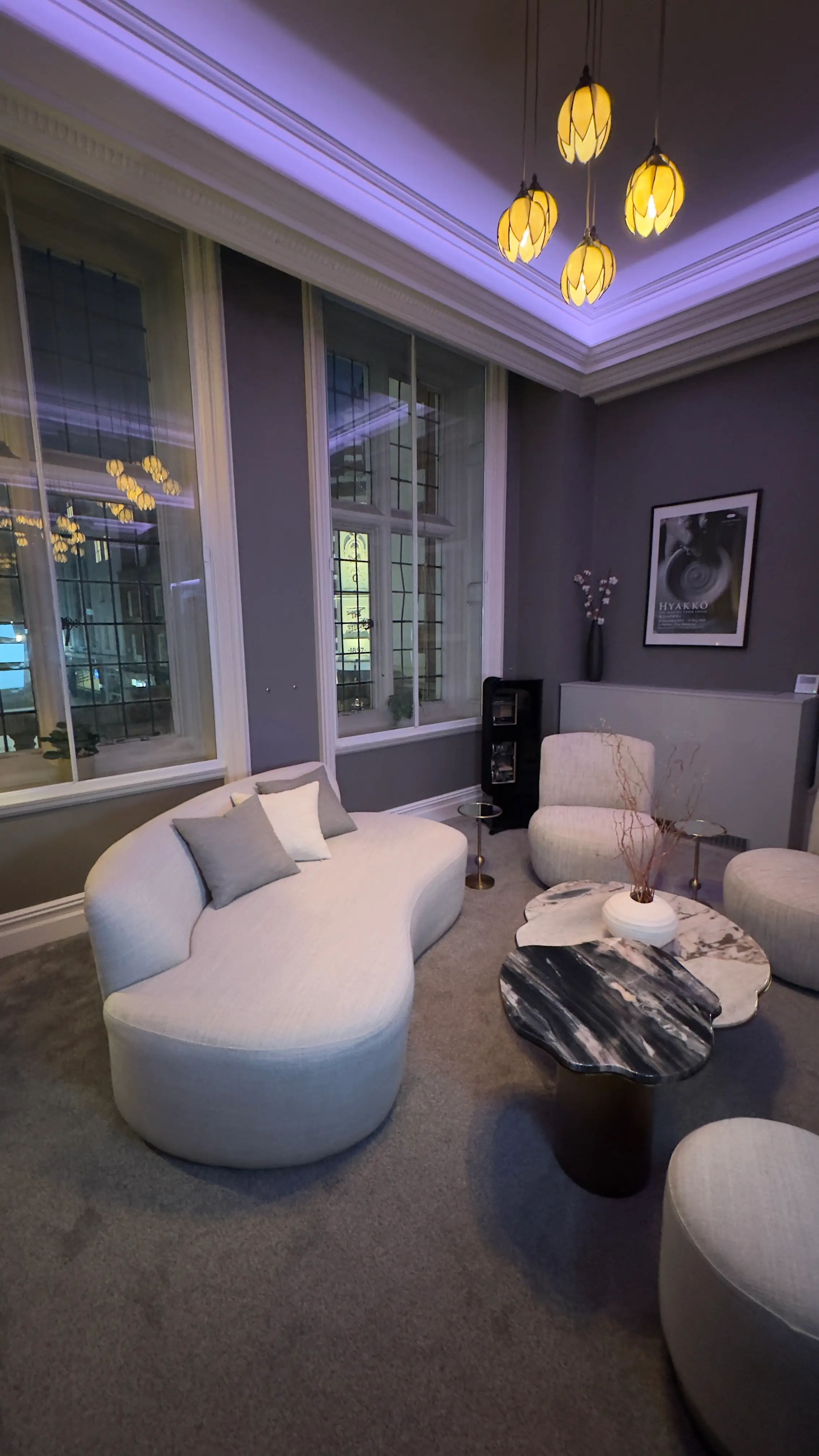 Reception room with curved upholstery, stone coffee table and floor lighting